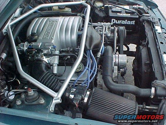 Engine bay of a 1992 Ford Mustang with a silver intake manifold and a Duralast battery