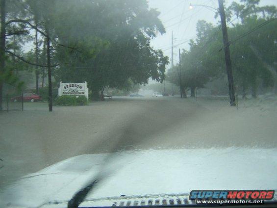 Flooded street with a white car and a red car visible