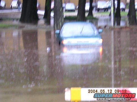 Teal sedan partially submerged in floodwater, front view. Date stamp reads 2004.05.12