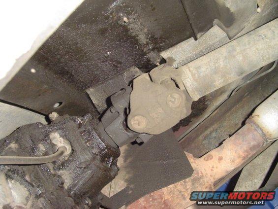 Underside of a vehicle showing the transmission, driveshaft, and exhaust pipe