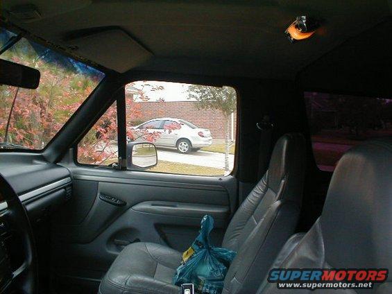 Interior view from driver's seat, looking out passenger window at a silver sedan parked in driveway