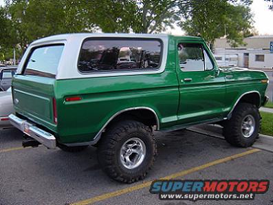 Green Ford Bronco with a white top, lifted with large tires, viewed from the rear three-quarter angle
