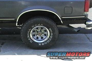 Rear wheel and fender of a dark-colored SUV. Tire has 'BAJA RADIAL' text