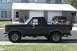 1989 Ford Bronco - Side view of a dark gray two-door Ford Bronco with a black top and a spare tire mounted on the rear.