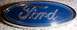 1997 Ford Taurus - Close-up of a blue Ford oval emblem with chrome trim, likely a grille or tailgate badge.