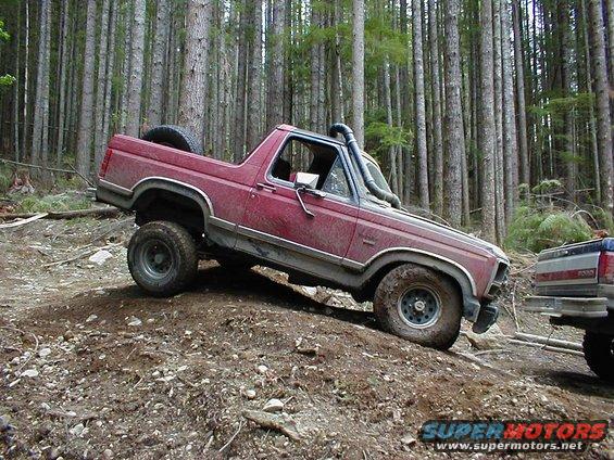 Red 1983 Ford Bronco with snorkel driving off-road