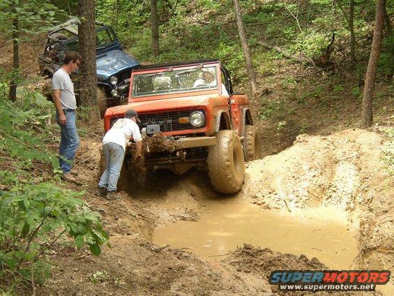 Orange first-generation Ford Bronco stuck in mud pit with another Jeep behind it