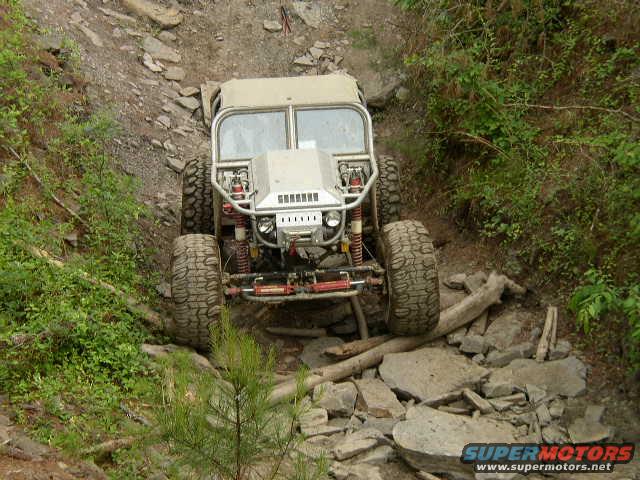 Off-road vehicle with large tires navigating a rocky trail