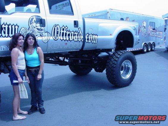 Silver lifted pickup truck with "Offroad.com" graphics and a tandem-axle trailer