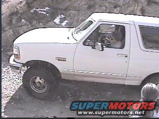 1993 Ford Bronco driving on a dirt path with rocky terrain