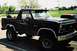 1985 Ford Bronco - This black 1985 Ford Bronco features a roof rack with decorative smiley face lights and a spare tire mounted in the bed.