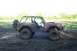 1974 Ford Bronco - Mud-covered 1974 Ford Bronco with a roll cage and spare tire sits in a muddy field.