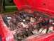 1989 Jeep YJ - The engine bay of a red 1989 Jeep YJ, showing the engine and various components with the hood raised.