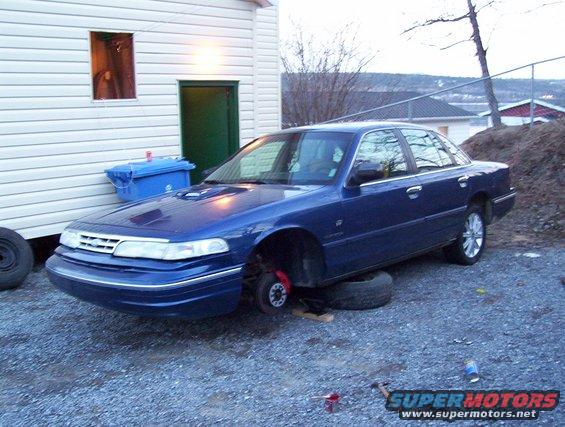 Blue 1995 Ford Crown Victoria with front wheels removed, resting on tires