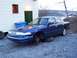 1995 Ford Crown Victoria - A blue 1995 Ford Crown Victoria is parked outside a building with its front wheels off.