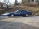 1995 Ford Crown Victoria - A blue 1995 Ford Crown Victoria is parked on a gravel lot next to a white car.