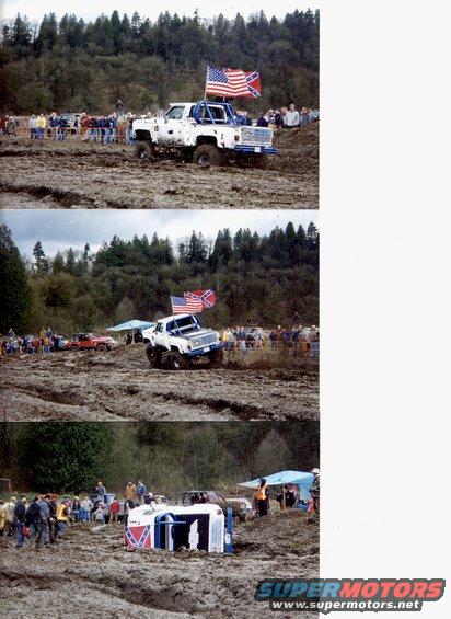 White pickup truck with American and Confederate flags in mud pit