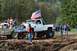 1990 Ford Bronco - Several lifted trucks are gathered in a muddy outdoor area, with spectators watching the event.