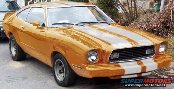 Orange coupe with white racing stripes, front quarter view. Visible front grille, headlights, and side mirror
