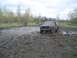 1981 Ford Bronco - A Ford Bronco navigates a challenging muddy terrain under an overcast sky.