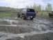 1981 Ford Bronco - A blue 1981 Ford Bronco navigates a muddy off-road course with another vehicle visible in the background.