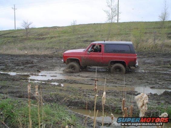 Red Chevrolet K5 Blazer stuck in mud, side view. Model years 1973-1991