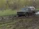 1981 Ford Bronco - This SUV is deep in the mud, struggling to move forward.