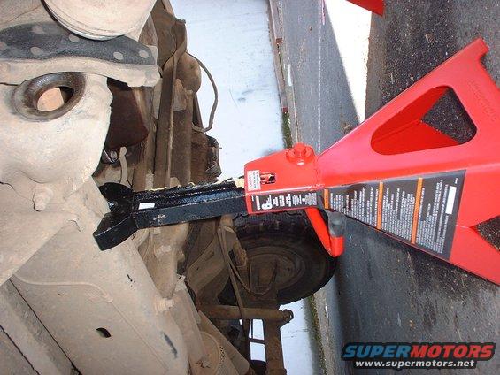 Undercarriage of a vehicle supported by a red jack stand