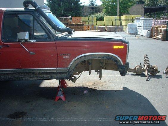 Red Ford Bronco on jack stands, front axle removed. Has a snorkel. Looks like it's being worked on