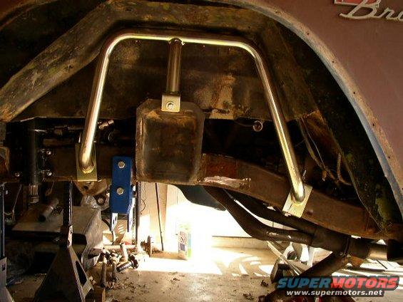 Underside of a vehicle showing frame modifications and a roll cage being installed. Some parts are on jack stands