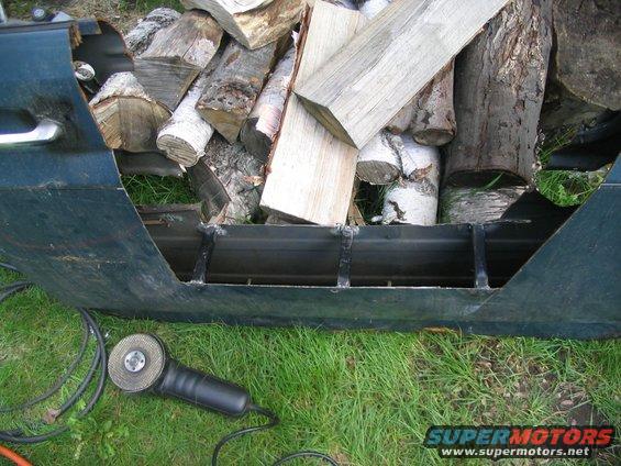 Cut-off vehicle door filled with firewood, angle grinder nearby