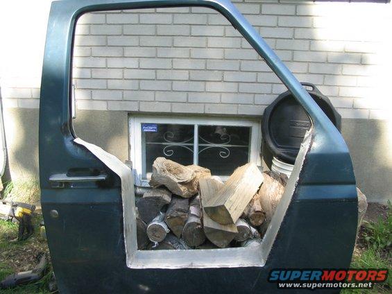 Green car door filled with firewood, seen from the side