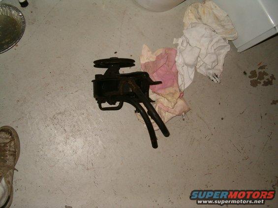 power steering pump with pulley and hoses, sitting on concrete floor next to rags