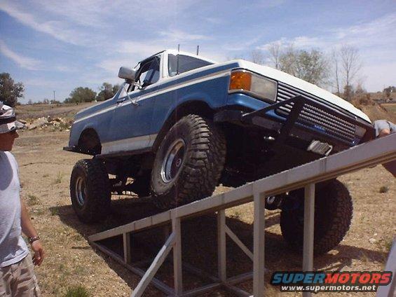 Blue and white lifted 1987 Ford Bronco on a ramp