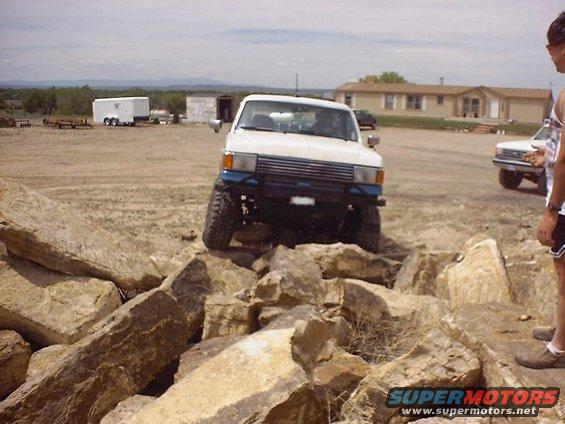 White 1984 Toyota 4Runner with blue bumper climbing over large rocks