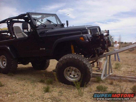 Black Jeep Wrangler on a metal ramp with people watching