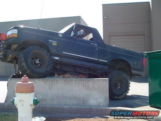 1993 Ford Bronco parked on concrete barrier with large tires