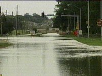 Flooded street with traffic lights and some buildings visible