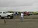 1978 Ford Bronco - Several off-road vehicles are gathered on a sandy beach under an overcast sky.