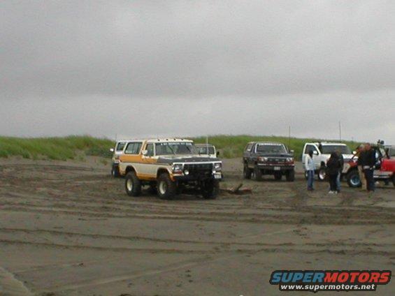 1978 Ford Bronco on a sandy beach, two-tone paint, lifted suspension, front 3/4 view