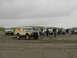 1978 Ford Bronco - A group of people and several off-road vehicles gather on a sandy beach under an overcast sky.