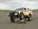 1978 Ford Bronco - This lifted 1978 Ford Bronco, sporting a "BIG BRONCOS 4X4 CLUB" sticker, navigates a sandy beach with a driftwood log nearby.