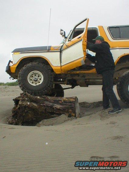 Yellow and white 1978 Ford Bronco with door open on a sandy beach