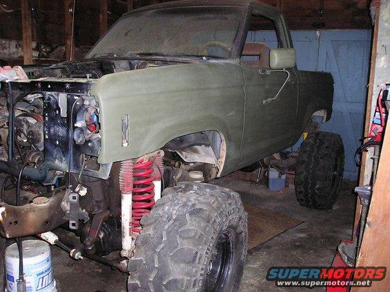 Green Ford Bronco II in garage, front end disassembled, lifted suspension, large tires