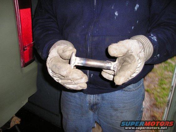 Gloved hands holding a metal exhaust pipe section
