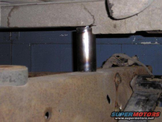 Close-up of a rusty vehicle frame with a metal cylinder extending upwards