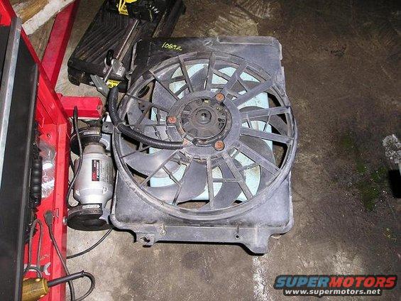 Radiator fan assembly with visible number 10892, resting on a concrete floor next to a red tool cart