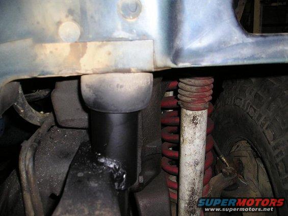 Close-up of suspension parts, including a shock absorber and red coil spring