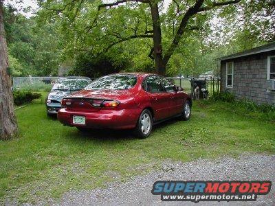 Red 1997 Ford Taurus, rear view, parked on grass with another car behind it
