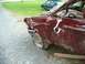 1990 Ford F-150 - A severely damaged maroon pickup truck sits on a gravel lot, with another vehicle visible in the background.
